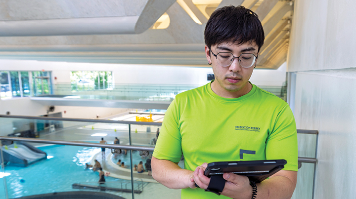 A man staring at a device with an indoor pool in the background