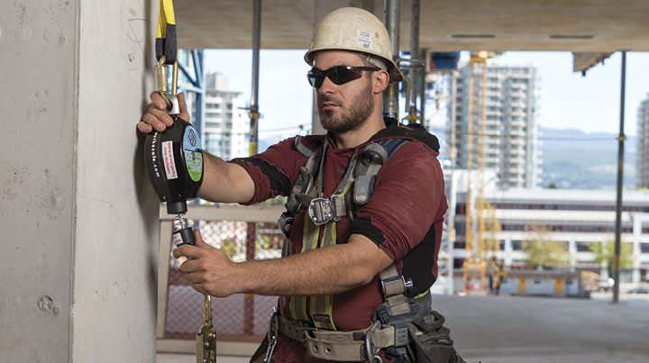 A construction worker securing their fall prevention device