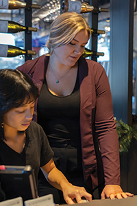 Restaurant staff stand together near a point-of-sale counter in a hospitality setting.