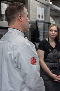 Restaurant staff gathered in a commercial kitchen for a workplace discussion.