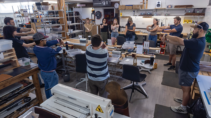 Workers participating in a workplace stretch and warm-up session inside a manufacturing workshop.