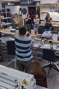 Workers participating in a workplace stretch and warm-up session inside a manufacturing workshop.